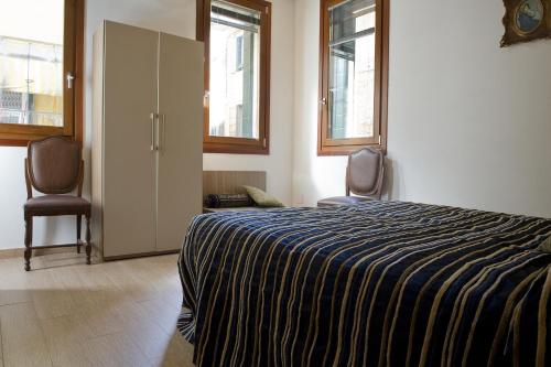 1 dormitorio con 1 cama, 2 sillas y ventanas en San Marco - Rialto with WIFI, en Venecia