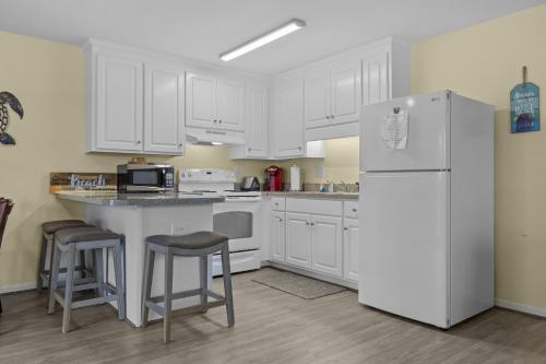 uma cozinha com armários brancos e um frigorífico branco em Boardwalk Shores C Duplex em Atlantic Beach