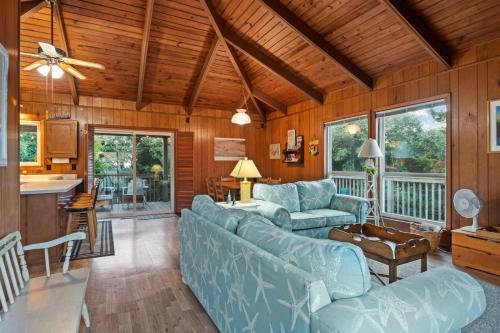 sala de estar con sofás azules y cocina en Dogwood Treehouse home, en Pine Knoll Shores