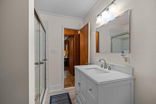 a white bathroom with a sink and a mirror at Dogwood Treehouse home in Pine Knoll Shores