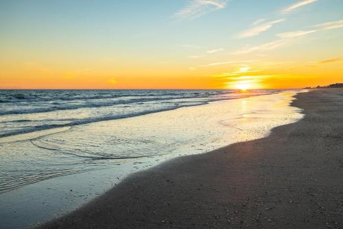a sunset on a beach with the ocean at Dogwood Treehouse home in Pine Knoll Shores