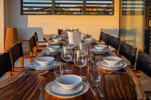 a long wooden table with plates and glasses on it at Villa Wahoo in Jan Thiel