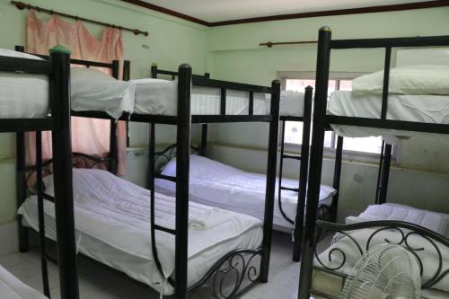 three bunk beds in a room with a fan at Rainbow Hotel Vientiane in Vientiane