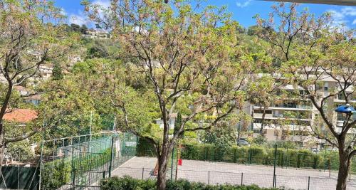 a view of a park with trees and a fence at Très beau deux pièces in Menton