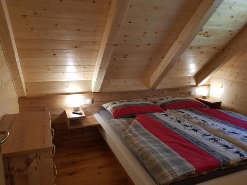 een slaapkamer met een bed op een houten zolder bij Premiumalmhütte Wiedhupf in Peterdorf
