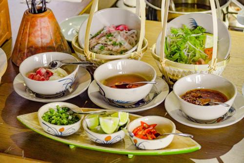 a table topped with bowls of soup and bowls of food at Seahorse Signature Danang Hotel by Haviland in Da Nang