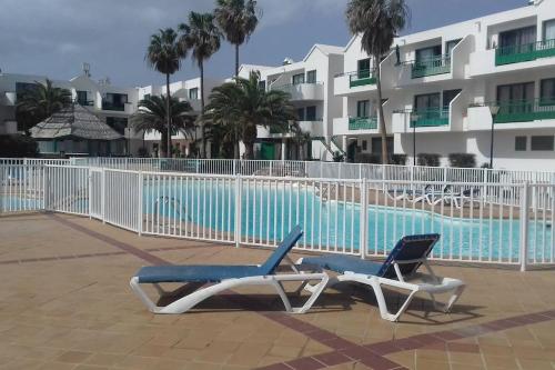 two lounge chairs sitting next to a swimming pool at Ap 1ª línea Playa Las cucharas in Costa Teguise