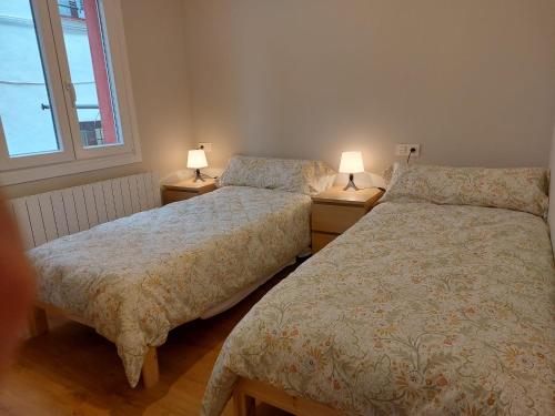 dwa łóżka w pokoju z dwoma lampami na stołach w obiekcie Habitación en apartamento con zonas comunes compartida H3 w mieście Bilbao