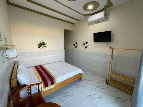 a bedroom with a bed and a tv on the wall at T'H Homestay in Mui Ne