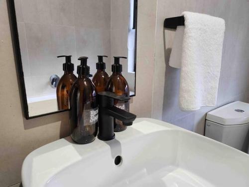 a bathroom sink with four bottles sitting on it at Manelo in Fourways in Fourways