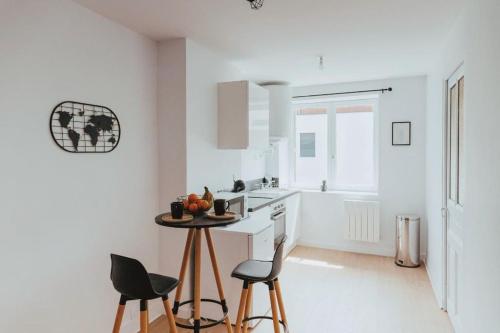 a white kitchen with a table and two chairs at NEPTUNE - Appartement Moderne & élégant in Saint-Étienne