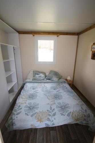 Bett in einem kleinen Zimmer mit Fenster in der Unterkunft Camping du Villard in Thorame-Basse