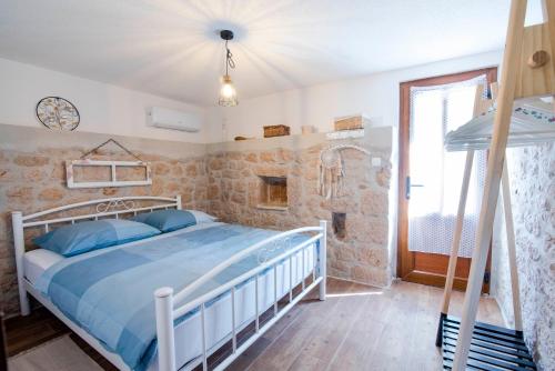 - une chambre avec un grand lit dans une pièce aux murs en pierre dans l'établissement Villa Vita, à Trilj