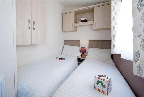 2 camas individuais num pequeno quarto com uma pequena mesa em L76 Rickardos Holiday Lets em Mablethorpe