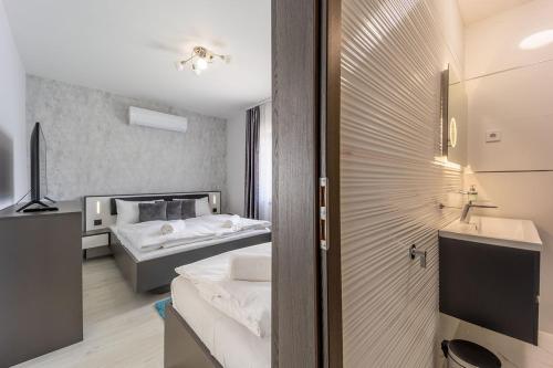 a room with two beds and a bathroom with a television at Sóstó Pihenőház By BLTN in Siófok