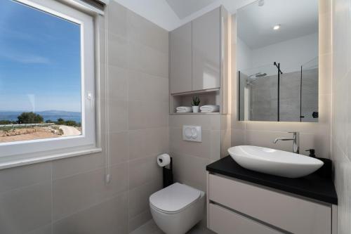 ein Bad mit einem Waschbecken, einem WC und einem Fenster in der Unterkunft Villa Ora with Heated pool, Whirlpool, 4 bedrooms in Grohote