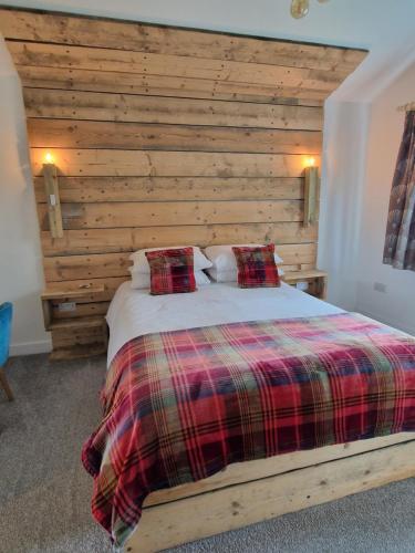 um quarto com uma cama e uma parede de madeira em Byre 1 em Stirling