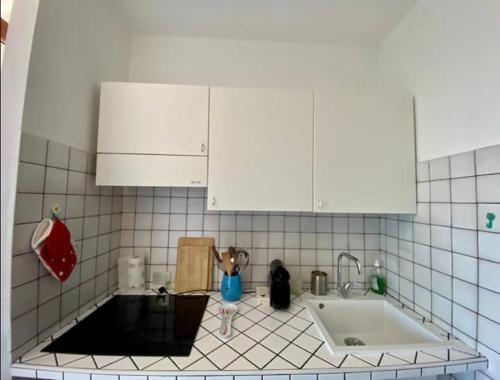 a kitchen with a sink and a white tiled wall at Stintino casa panoramica a 500 mt dal mare in Stintino