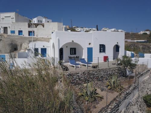 a white house with blue chairs in front of it at Villa Solasta in Santorini in Akrotiri