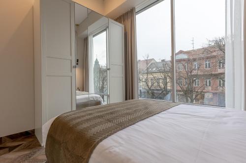 1 dormitorio con cama grande y ventana grande en LAISVĖ BOUTIQUE APARTMENTS en Kaunas