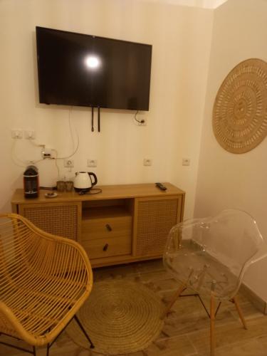 a living room with a tv and a table and chairs at Les chambres d'hôtes du Relais d'Aguilar in Tuchan