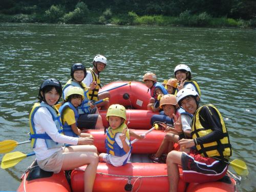 a group of people on a raft on a river at Fujio Pension Madarao Apartment Hotel & Restaurant in Iiyama
