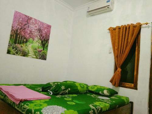 een kamer met een groen bed met een foto aan de muur bij Homestay Nova Klayar in Kalak
