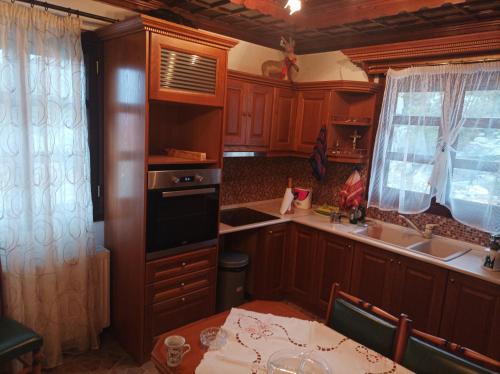 a kitchen with wooden cabinets and a table and a sink at Stelios house in Theologos
