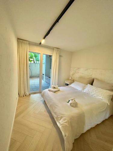 une chambre avec un grand lit blanc et une fenêtre dans l'établissement CAM0 - appartement 2 chambres en rez-de-terrasse, à Cannes