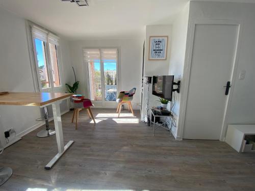 a living room with a table and a desk at CARQUEIRANNE STUDIO DE CHARME PROCHE PLAGES in Carqueiranne