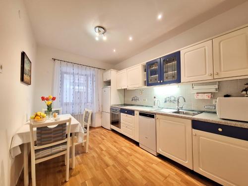 a kitchen with white cabinets and a table and a table and chairs at Apartment Taya in Piran