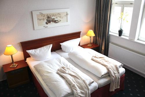 a bedroom with two beds with white sheets and two lamps at Parkhotel Fischer in Wernigerode