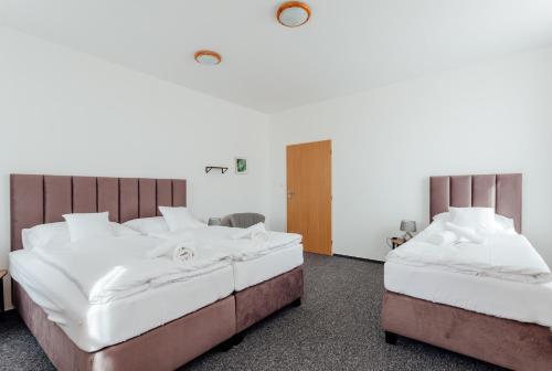 two beds in a room with white sheets at Black M - Penzión - Reštaurácia in Banská Štiavnica