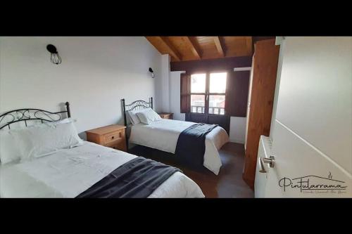 1 dormitorio con 2 camas y ventana en Pintularrama - Casa Rural en Póo de Llanes en Poo de Llanes