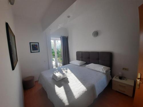 sypialnia z łóżkiem z białą pościelą i oknem w obiekcie Banjol - ARBA w mieście Banjol