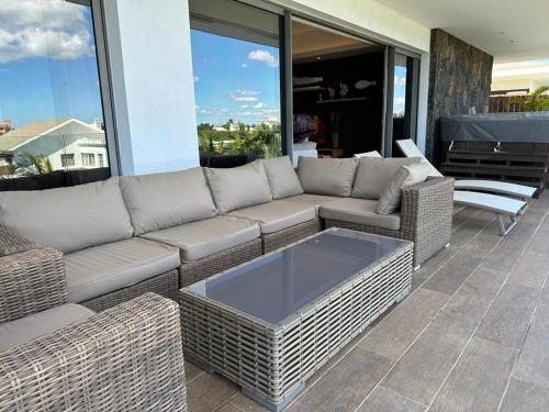 a patio with a couch and a coffee table at Une Sublime Villa sur le Toit pour des Vacances Inoubliables in Pereybere