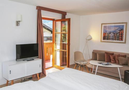 sypialnia z łóżkiem, telewizorem i kanapą w obiekcie Hotel Sonnenhof - bed & breakfast & appartements w mieście Innsbruck