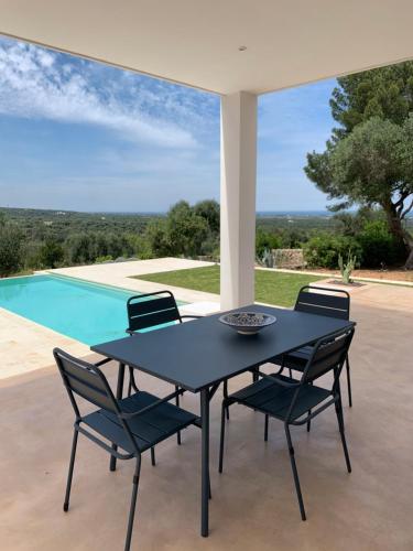 a black table and chairs on a patio with a pool at Villa Pasquy in Specchiolla 