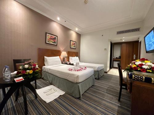 um quarto de hotel com duas camas e uma televisão de ecrã plano em Al Massa Dar Al Fayzeen Makkah em Meca