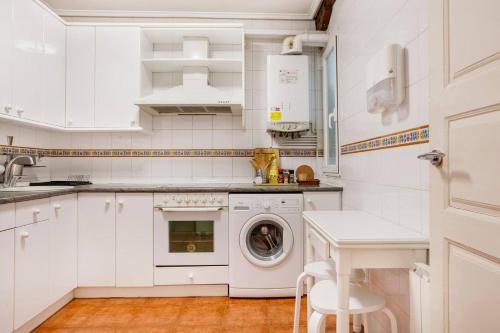 a white kitchen with a washing machine and a sink at Habitaciones en la Plaza Nueva in Bilbao