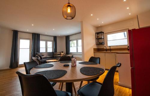 ein Wohnzimmer mit einem Tisch und Stühlen sowie eine Küche in der Unterkunft Südschleife Appartements - App. 2 - WLAN - Direkt am Ring in Reimerath