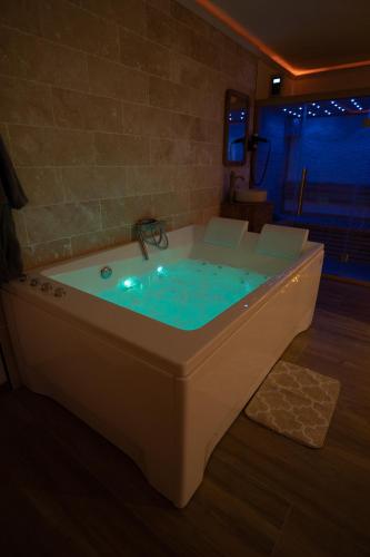 a bath tub with blue water in a room at Capsule Marrakech I Chicha I Sauna I Balnéo I Console PS5 I Cinéma in Trith-Saint-Léger