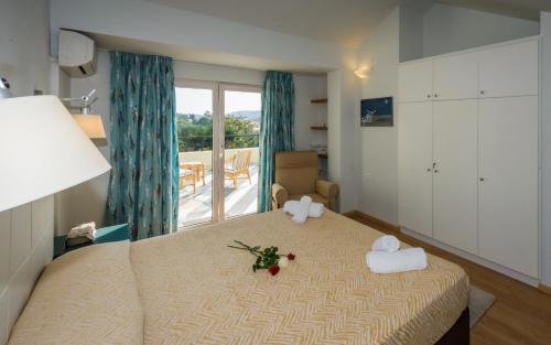 a bedroom with a bed with towels and a balcony at Helion Apartments in Gouvia