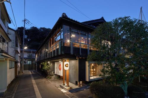 a house with a balcony on a street at night at 城崎温泉 旅館 つばき乃 - Kinosaki Onsen Ryokan Tsubakino in Toyooka