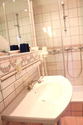 a bathroom with a white sink and a mirror at Parkhotel Fischer in Wernigerode