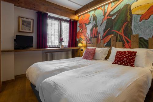 布勒伊－切爾維尼亞的住宿－Hotel & Ristorante Serenella，卧室配有一张大床,墙上挂有绘画作品
