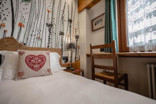 a bedroom with a bed with a heart pillow on it at Hotel & Ristorante Serenella in Breuil-Cervinia