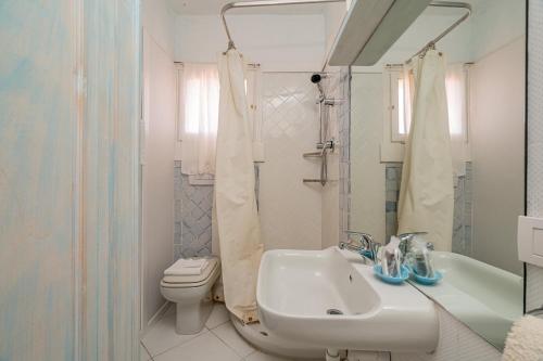 La salle de bains blanche est pourvue d'un lavabo et de toilettes. dans l'établissement Casa Silvana by Wonderful Italy, à Porto Cervo