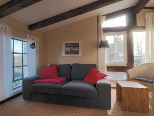 - un salon avec un canapé gris et des oreillers rouges dans l'établissement Auf den Hoefen Fewo 13, à Kühlungsborn