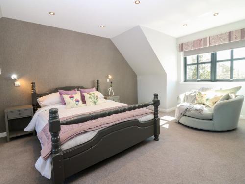 a bedroom with a large bed and a chair at Woodend Croft in Ellon